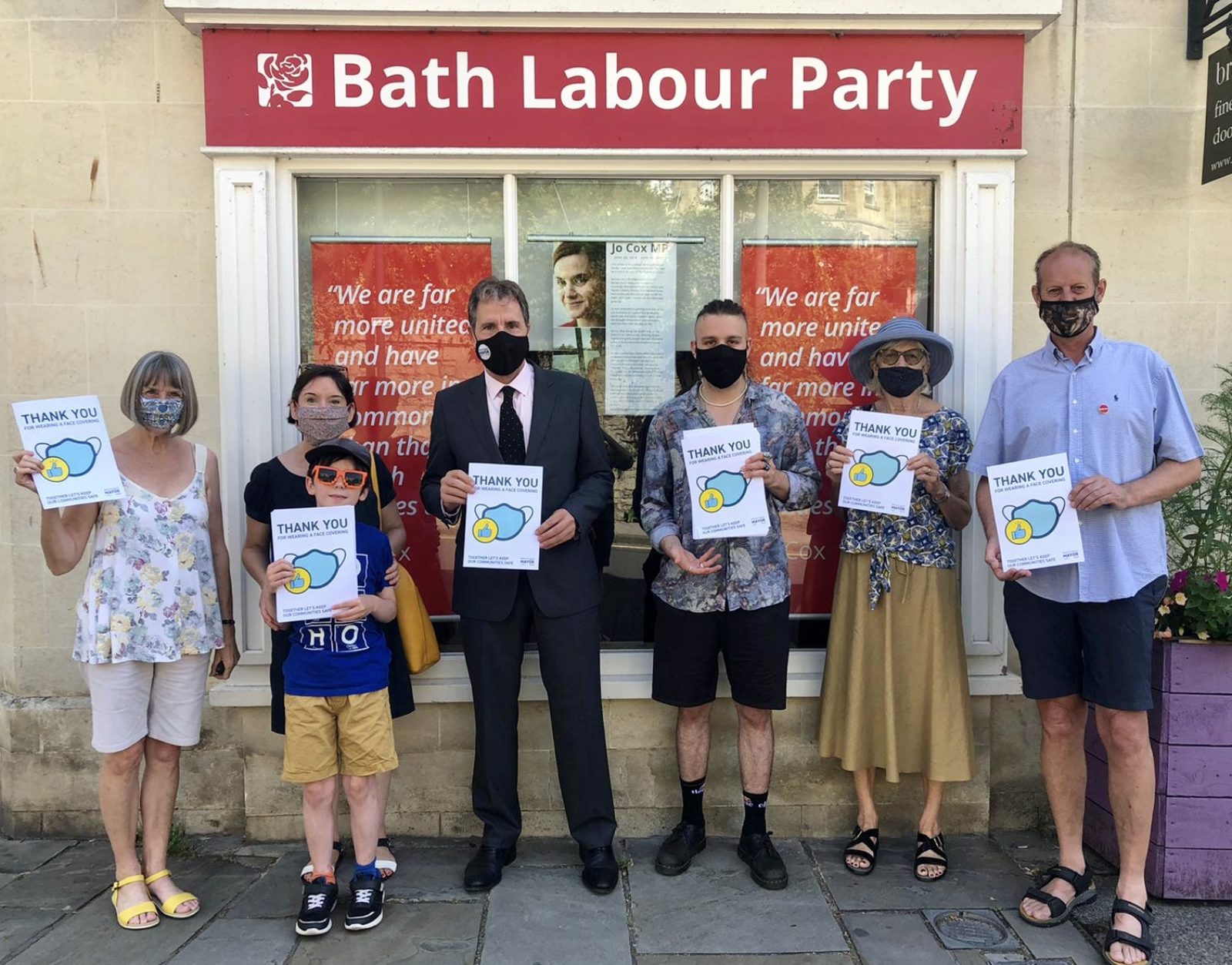 Labour Metro Mayor Dan Norris stands outside the CLP office with members, holding "thank you for wearing a mask" posters