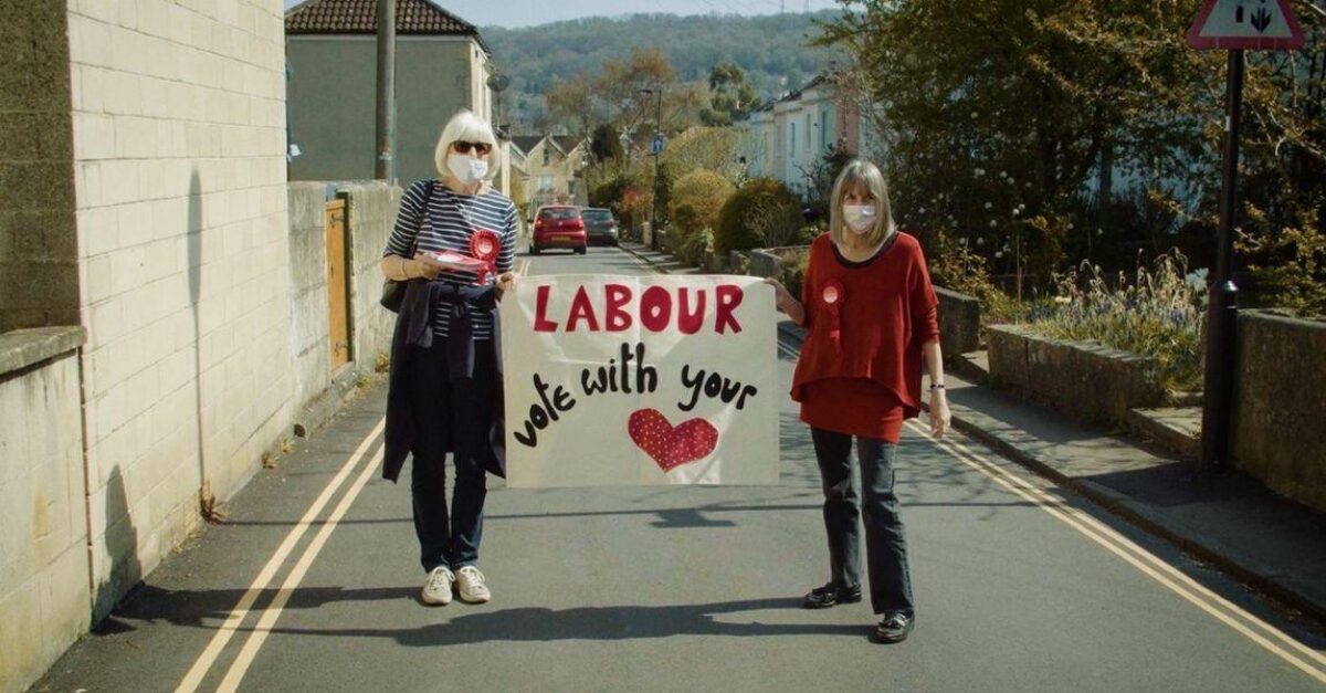 Labour members campaigning for the Metro Mayor, wearing masks. They hold a Labour banner that says "Vote With Your Heart"